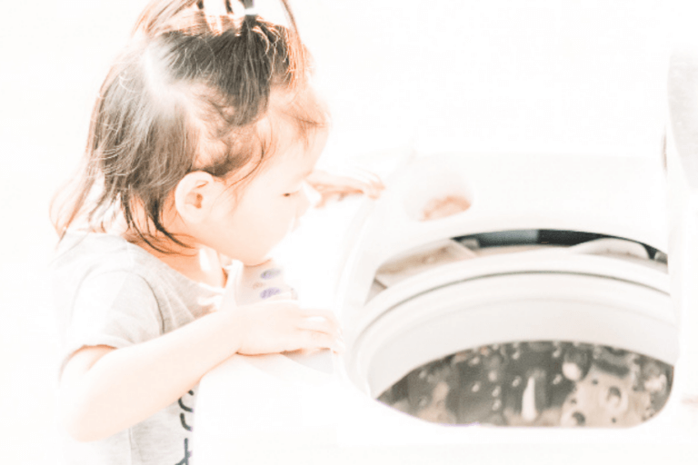 Little girl peering into washing machine