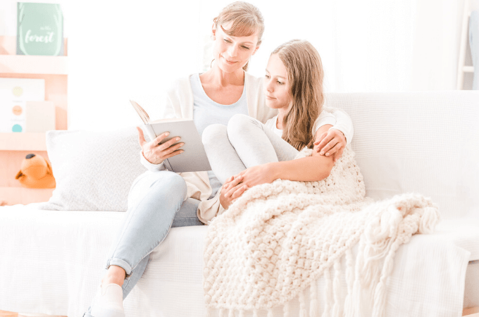 Two images of a mother and daughter snuggled together on the sofa reading a book together - concept of importance of reading to older children