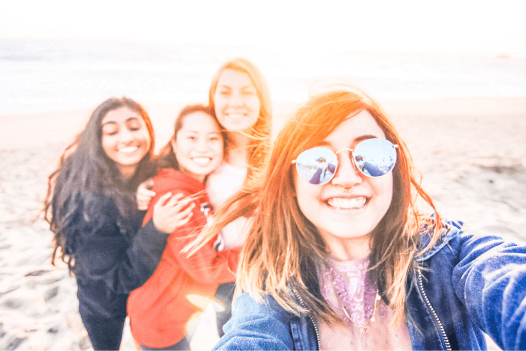 Image of teenage girls on beach taking a selfie representing the concept of happy and confident teens teens
