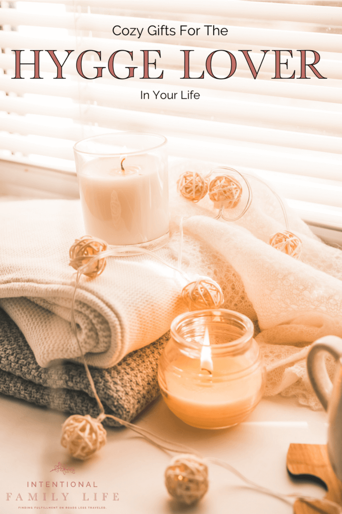 A warm candlelight image of hot chocolate and snacks with cozy blankets and home decorations suggesting hygge gifts; hygge gift ideas; and a hygge lifestyle