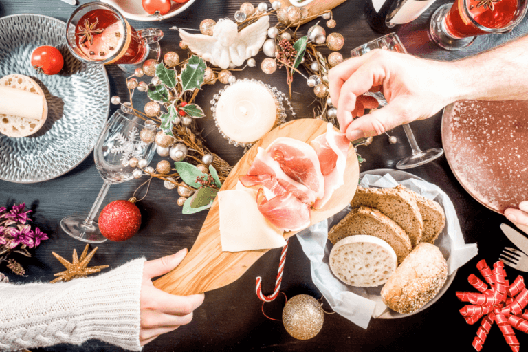 a table beautifully and festively set with delicious looking winter comfort foods including a charcuterie board with proscuitto and the idea of a warm gathering of friends and family