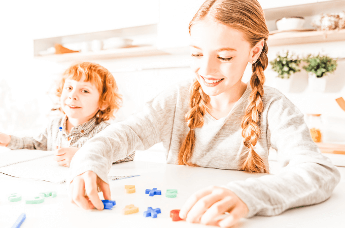 image of young girl playing math board game with manipulatives and smiling
