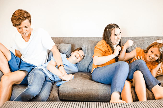 family of teens laughing and playing with one another suggesting the concept of family bond