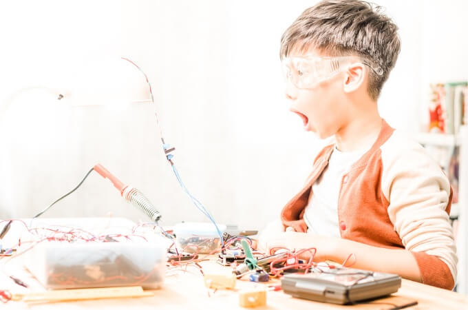Image of really excited young boy exercising creative thinking and being amazed at what he has created