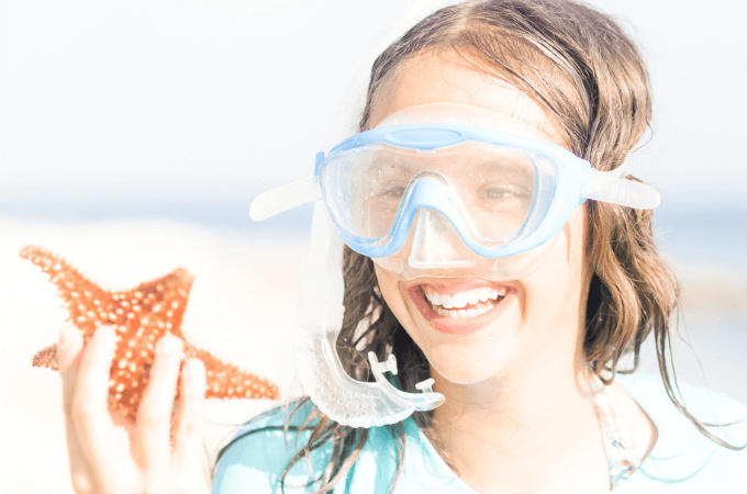 image of excited young girl hold starfish - concept of books about ocean animals