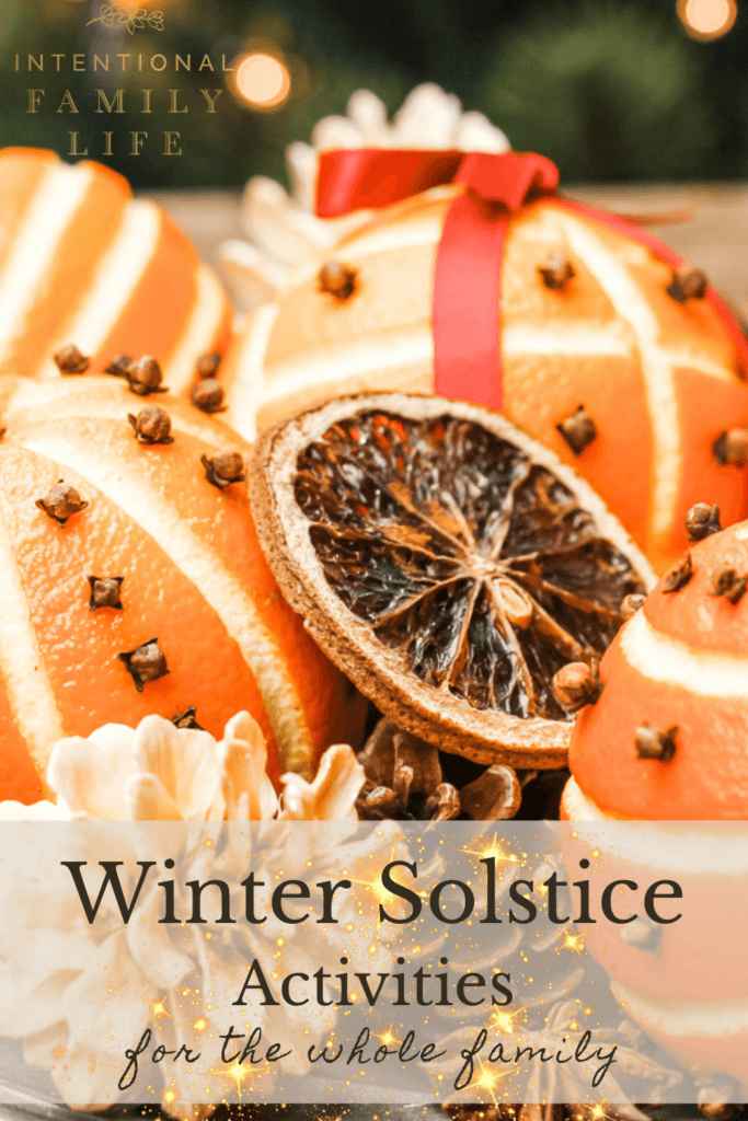 a gorgeous close up image of orange pomanders pierced with closed and decorated with ribbons as well as dried slices of orange - suggesting a wonderful winter solstice activity for families